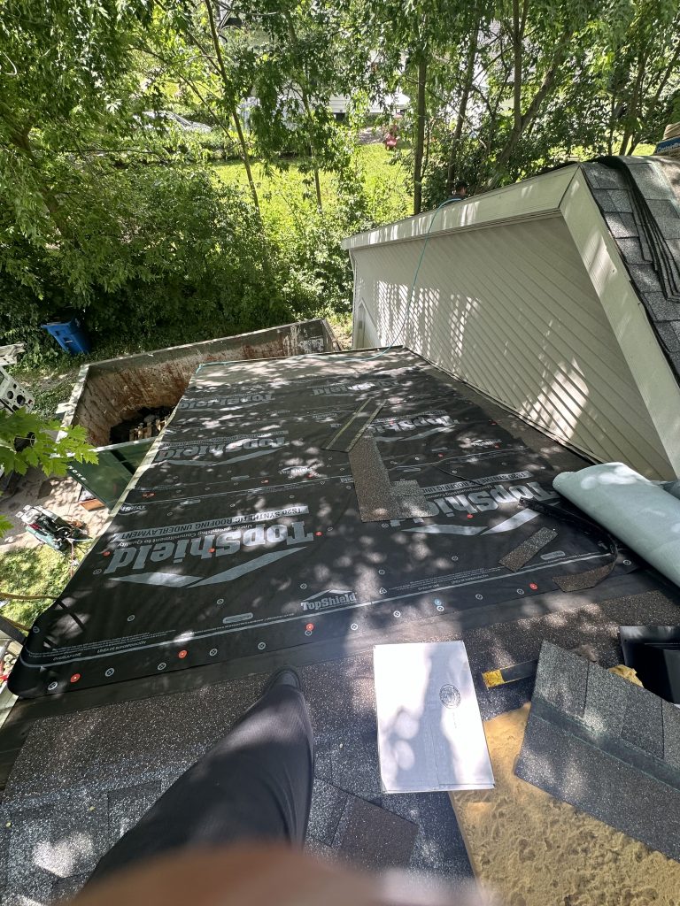 Looking down a steep roof incline while roofers work on a roof replacement job